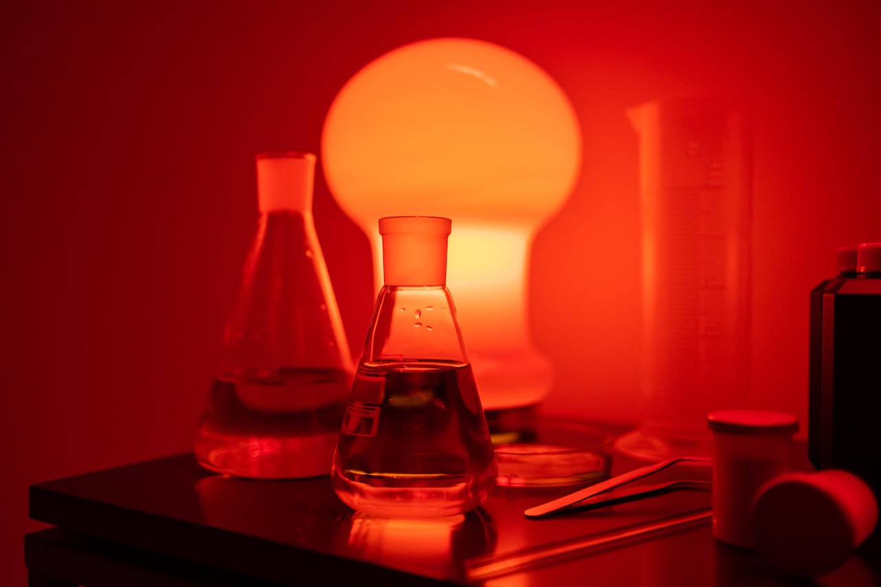 Laboratory flasks and equipment illuminated by moody red light, creating a dramatic effect.